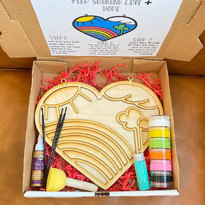 Wood Painting Kit featuring a Heart that holds inside it a Rainbow, clouds, sun and a tree creating the perfect landscape. Kit comes with glue, brushes, paint and instructions